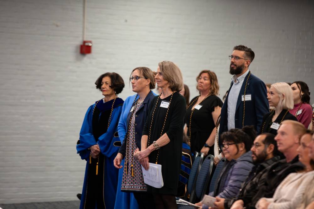Individuals stand and listen to speaker